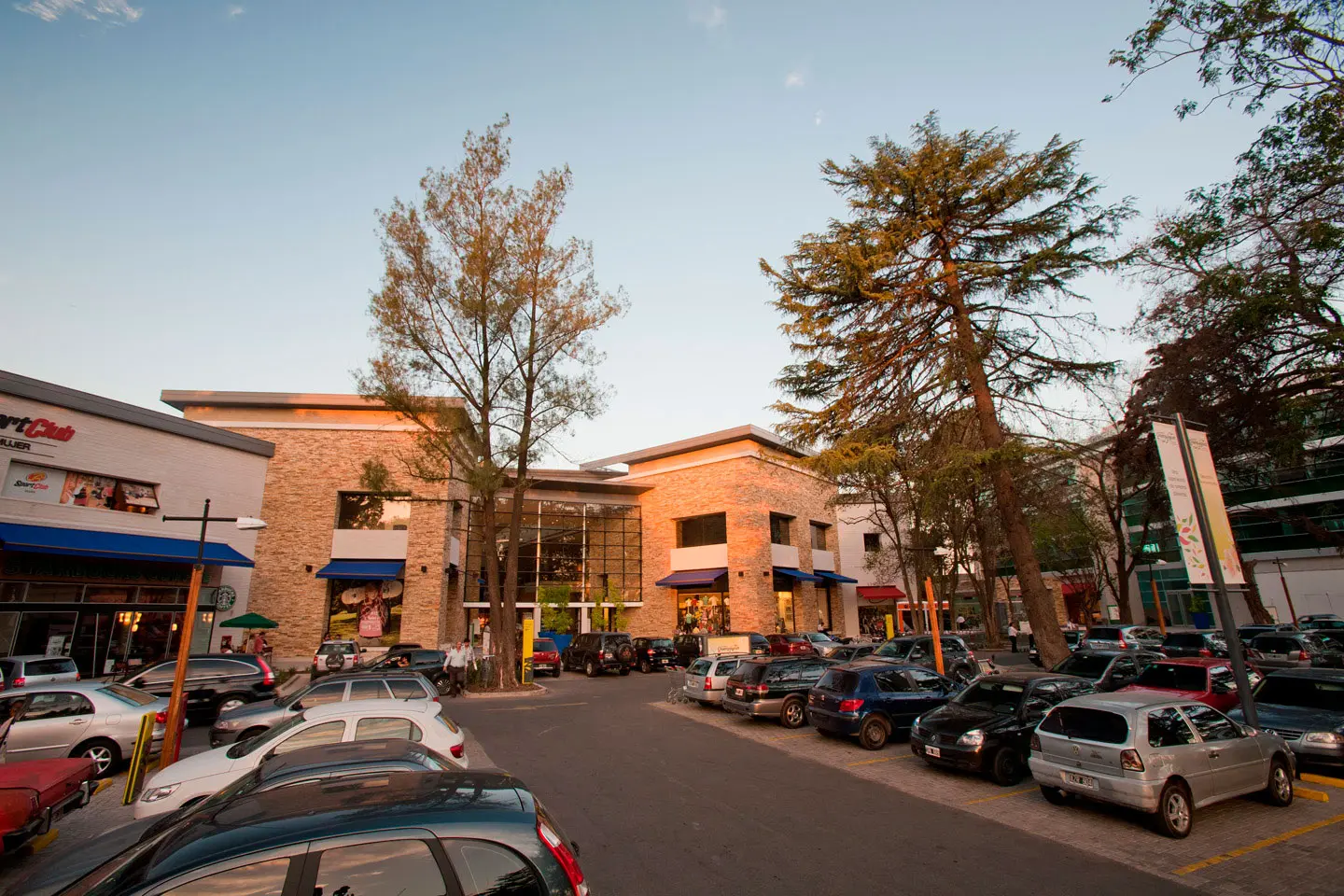Vista de Paseo Champagnat con el estacionamiento y los árboles altos